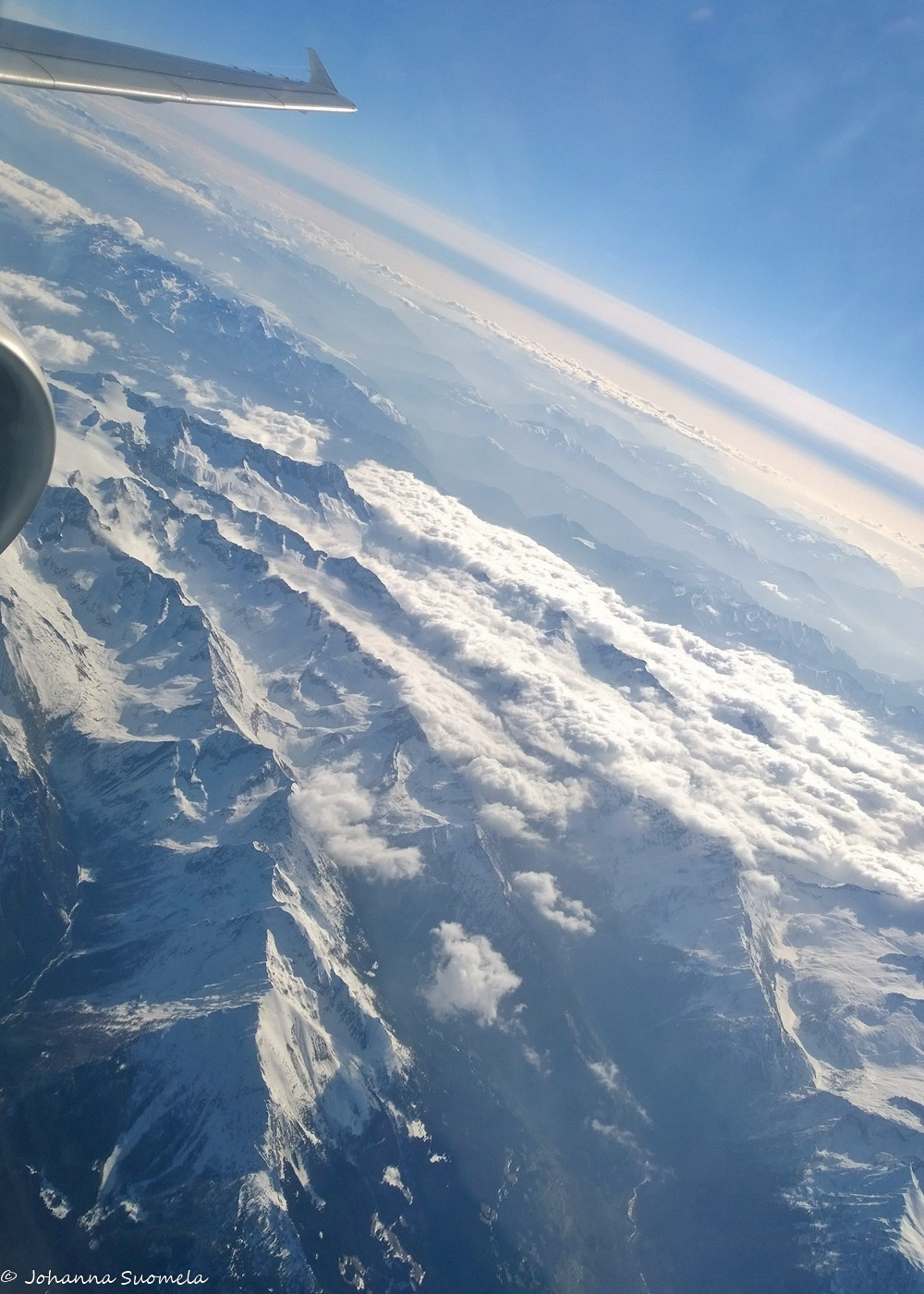 Alppien ylitys lentokoneen ikkunasta.