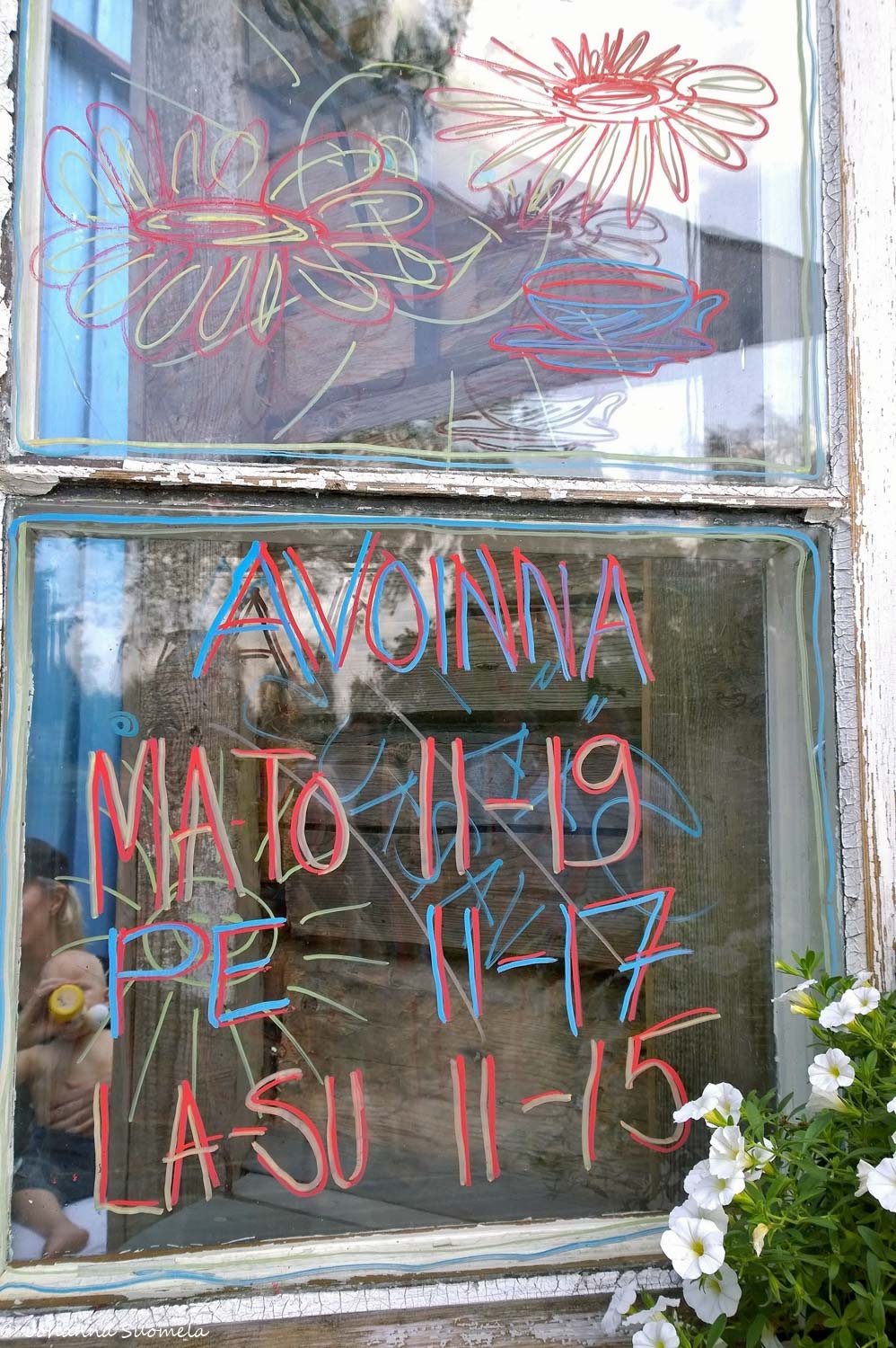 Sinisen kahvilan ikkunaan kirjoitetut aukioloajat