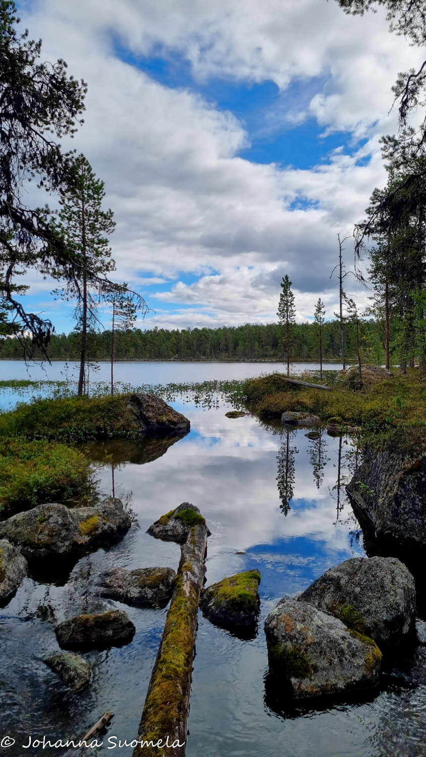 Sininen taivas pilkottaa järvellä Inarissa.